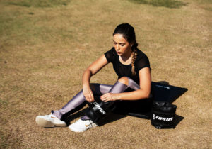 imagem de mulher sentada na grama colocando peso de tornozelo fokus