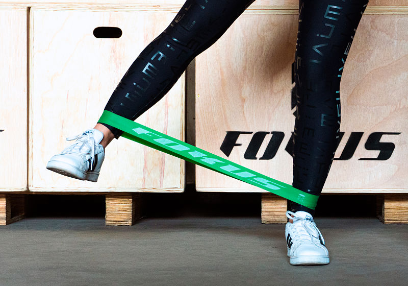 Imagem focada nas pernas de uma atleta realizando abdutor unilateral com mini band