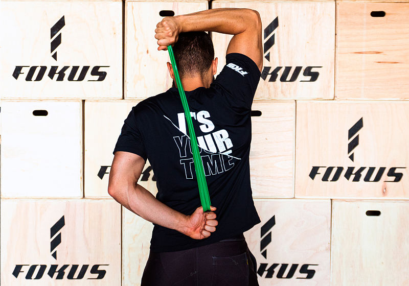 Imagem de um atleta de costas treinando tríceps francês com mini band