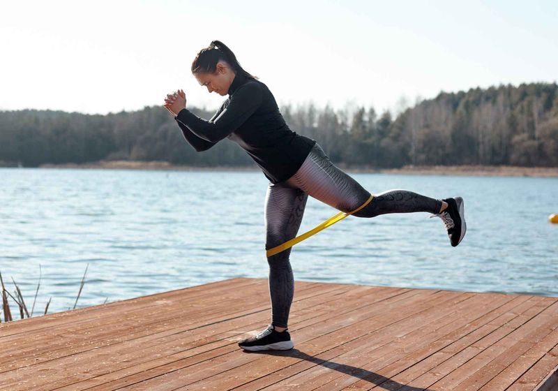 Imagem de atleta fortalecendo os glúteos com treino com elástico ao ar livre
