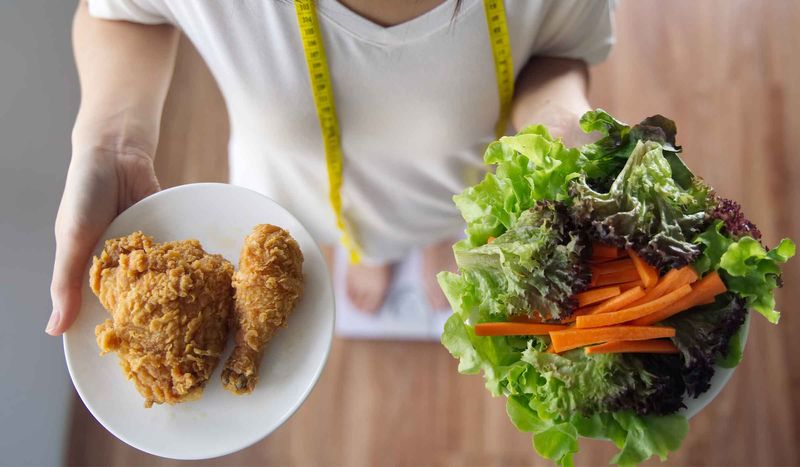 Imagem de uma pessoa servindo um prato de salada e um prato de frango